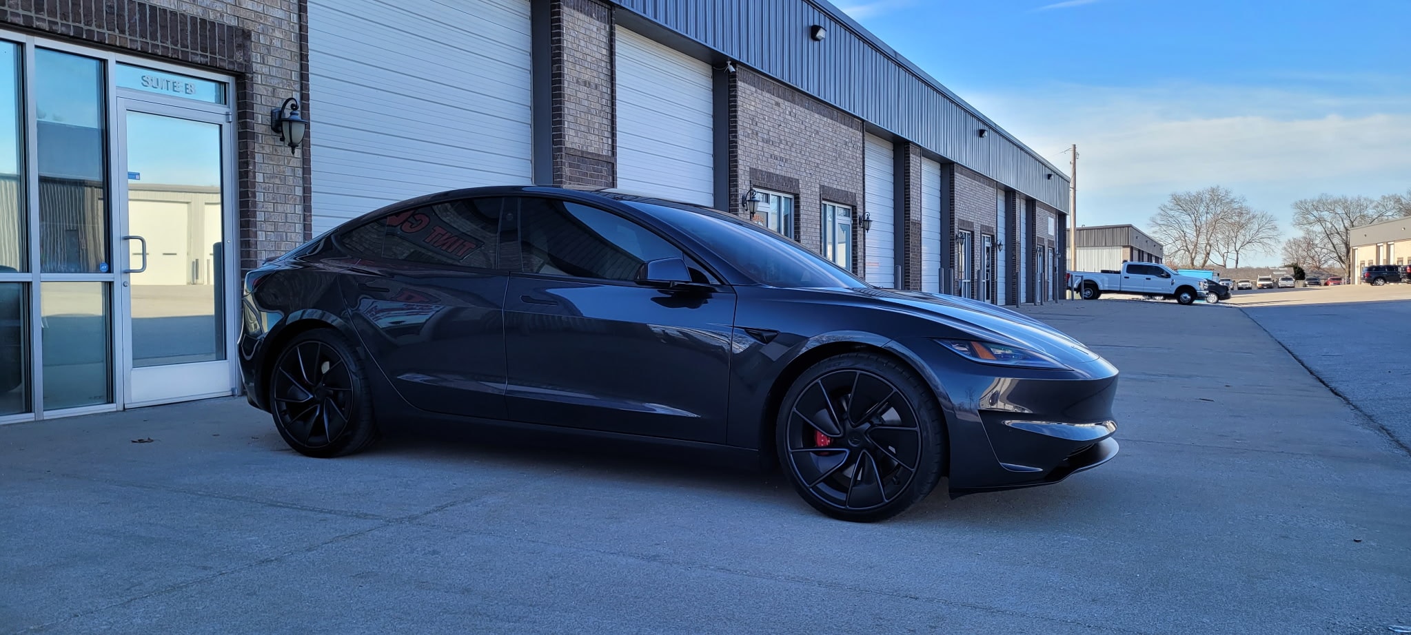 Black electric sedan parked at warehouse